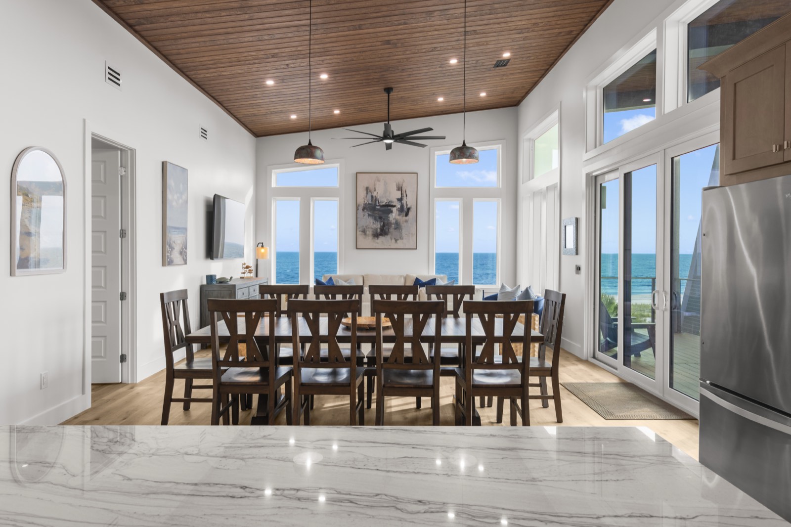 Oceanfront dining room with wood ceiling and Gulf view through floor-to-ceiling windows